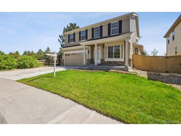 Two-story home featuring a lawn, neutral siding, an attached two-car garage, and a welcoming covered front porch at 16893 Trail View Cir, Parker, CO 80134