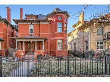 Striking red brick Victorian with turret, inviting front porch, and manicured front yard at 1351 N Franklin St, Denver, CO 80218
