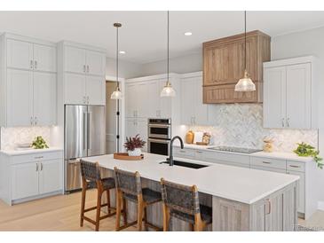 A modern, open kitchen with a large island, stainless steel appliances, and stylish pendant lighting at 1425 Burt Ave, Berthoud, CO 80513