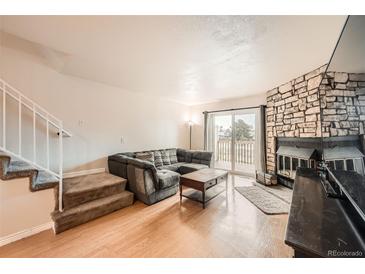 Inviting living room with stone fireplace, wood floors, and a comfortable sectional sofa at 1240 S Idalia St, Aurora, CO 80017