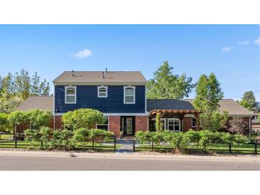 Charming two-story home with a beautiful blue and brick facade, surrounded by a well-manicured lawn at 3330 E Tennessee Ave, Denver, CO 80209