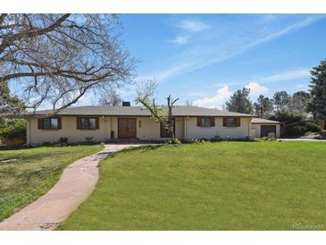 Ranch-style home with a green lawn, mature trees, stone walkway, and double door entry at 5460 S Locust St, Greenwood Village, CO 80111