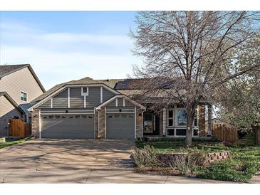 Charming exterior view of home featuring a three-car garage, gray siding, stone accents, and mature landscaping at 11785 W Belleview, Littleton, CO 80127