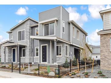 Contemporary home with gray siding, stone accents, and black metal fence at 4588 S Versailles St # B, Aurora, CO 80015