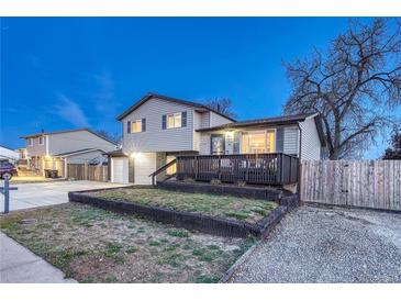 Charming two-story home featuring a welcoming front porch and landscaped front yard at twilight at 6550 W 74Th Pl, Arvada, CO 80003
