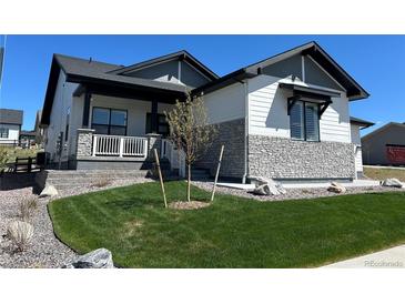 Charming home with a well-maintained lawn, stone accents, and inviting covered porch at 5492 Woodroot Pt, Castle Rock, CO 80104