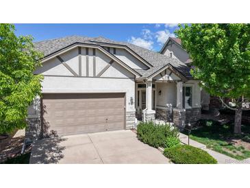 Charming home with a two-car garage, covered porch, and manicured landscaping under a bright blue sky at 6187 Reed Way, Arvada, CO 80003