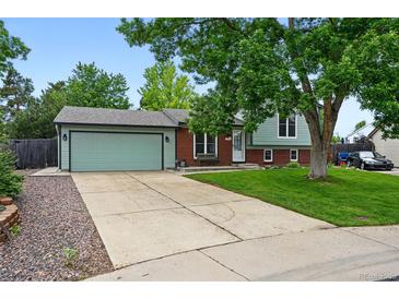 Charming home featuring a two-car garage, lush lawn, mature trees, and a brick and siding facade at 9315 Field Ln, Westminster, CO 80021