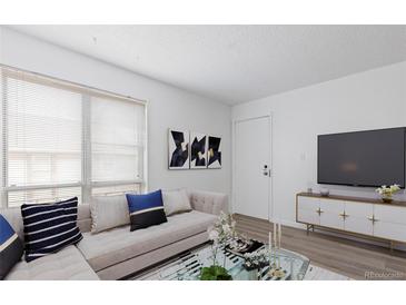 Bright living room features a decorative fireplace, large windows, and modern furnishings at 7185 S Gaylord St # G13, Littleton, CO 80122