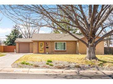 Charming single story home featuring a bright yellow front door and attached one car garage at 3925 Newland St, Wheat Ridge, CO 80033