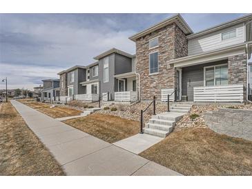 Modern townhome with stone and gray siding, welcoming front porch, and landscaping at 16700 Alzere Pl, Parker, CO 80134