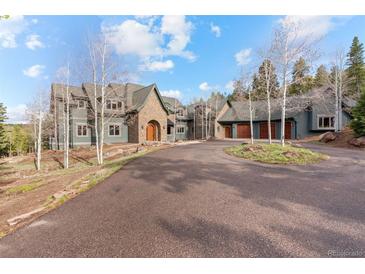 Beautiful home with a circular driveway and lush landscaping leading to attached garages at 11406 Conifer Ridge Dr, Conifer, CO 80433