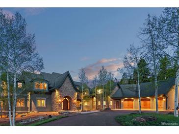 Stunning stone home with lush landscaping and mature trees, perfect for luxury living at 11406 Conifer Ridge Dr, Conifer, CO 80433