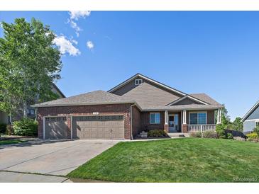 Charming single-story home with a brick facade, well-manicured lawn, and a three-car garage at 1758 Parkdale N Cir, Erie, CO 80516