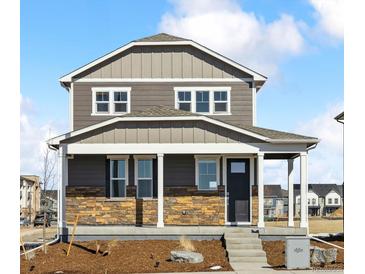 Charming two-story home featuring stone accents, a covered porch, and a well-manicured front yard at 22203 E 6Th Pl, Aurora, CO 80018