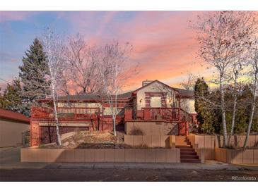 Charming multi-level home with a red-trimmed exterior and a spacious front deck, set against a colorful sky at 4215 W Byron Pl, Denver, CO 80212