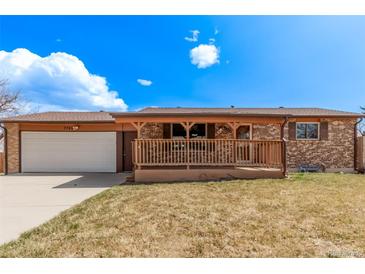 Charming brick home with a covered front porch and attached garage on a sunny day at 7720 Kendall St, Arvada, CO 80003