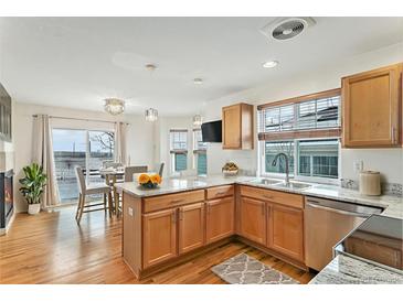 Bright kitchen featuring wooden cabinetry, granite countertops, stainless steel appliances, and hardwood flooring at 24285 E Wagon Trail Ave, Aurora, CO 80016