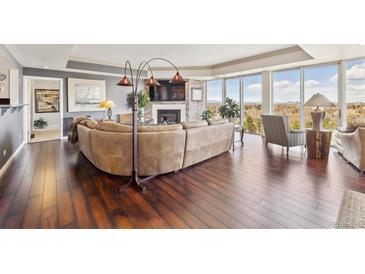 Bright living room featuring hardwood floors, floor-to-ceiling windows, and a cozy fireplace at 1900 E Girard Pl # 907, Englewood, CO 80113