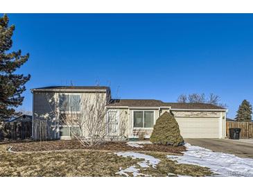 Tan two-story house with attached garage and landscaped yard at 11914 Bellaire Cir, Thornton, CO 80233