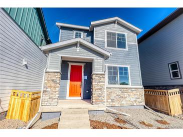 Charming two-story home with a bright red front door and stone accents at 21292 E 63Rd Dr, Aurora, CO 80019