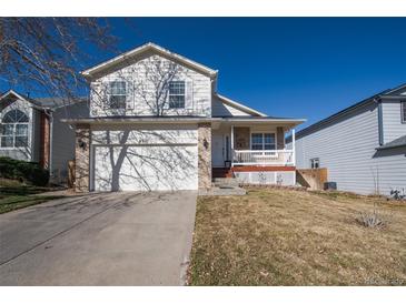 Two-story home with a two-car garage, a white porch, and a well-maintained front yard under a clear blue sky at 4931 S Danube St, Aurora, CO 80015