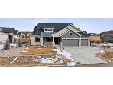 Gray exterior two-story house with stone accents, three-car garage, and landscaped yard at 528 Nesting Eagles Way, Berthoud, CO 80513