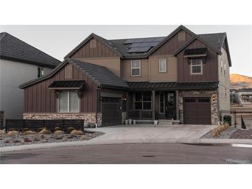 Two-story home with brown siding, stone accents, and solar panels at 15601 W Eureka Ave, Morrison, CO 80465