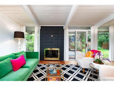 Bright living room featuring a sleek fireplace, modern furniture, and access to the outdoor garden through sliding glass doors at 1831 S Ivanhoe St, Denver, CO 80224