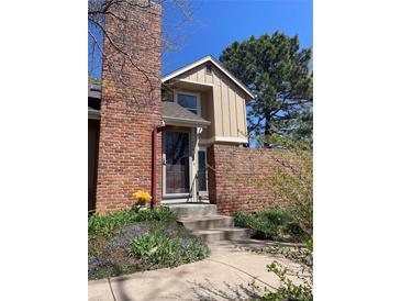 Charming two-story home with brick chimney, brick fence, colorful flower bed, and inviting front entrance at 11886 Elk Head Range Rd, Littleton, CO 80127