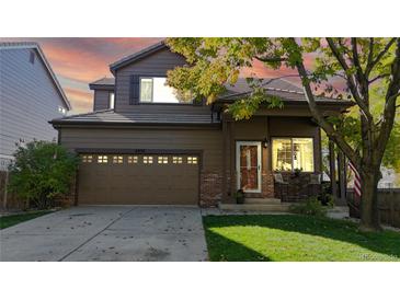 Charming two-story home featuring a well-maintained lawn, brick accents, and an attached two-car garage at 6898 W Rockland Pl, Littleton, CO 80128