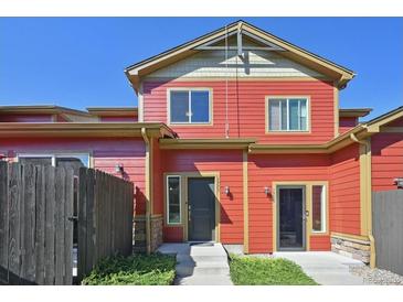 Charming red two-story townhome featuring well-kept landscaping and complementary architectural details at 1775 Aspen Meadows Cir, Denver, CO 80260