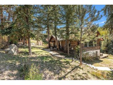 Charming log cabin with natural landscaping and mature trees at 25728 Stanley Park Rd, Evergreen, CO 80439