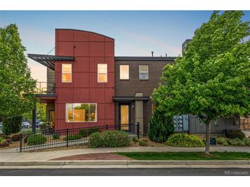 Modern townhome with a red exterior, brick accents, and well-maintained landscaping at 2110 W 67Th Pl, Denver, CO 80221