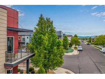 View of a modern home and street with mature trees and mountain views on a partly cloudy day at 2110 W 67Th Pl, Denver, CO 80221