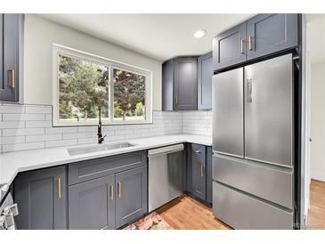 Charming kitchen features gray cabinets, stainless steel appliances, white subway tile, and views of the outdoors at 495 Quebec St, Denver, CO 80220