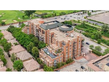 Brick condo building featuring balconies, patio, and roof deck is surrounded by trees and has a parking area at 2400 E Cherry Creek South Dr # 207, Denver, CO 80209