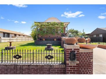 Charming brick home featuring a landscaped yard and unique architectural details on a sunny day at 5960 Glencoe St, Commerce City, CO 80022