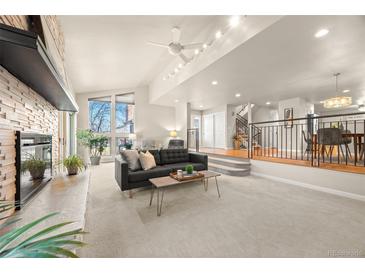 Bright living room boasts large windows, fireplace, and open floor plan to dining area at 2609 S Quebec St # 9, Denver, CO 80231