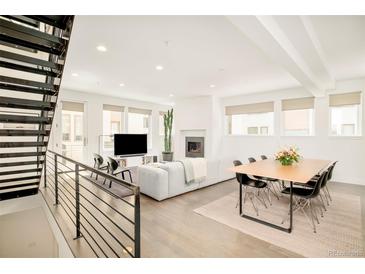 Bright and airy living room features an open floor plan, modern fireplace and staircase with metal railings at 1945 W 34Th Ave, Denver, CO 80211