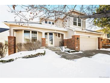 Two-story house with brick and siding exterior, attached garage, and snow-covered landscaping at 958 Bramblewood Dr, Castle Pines, CO 80108