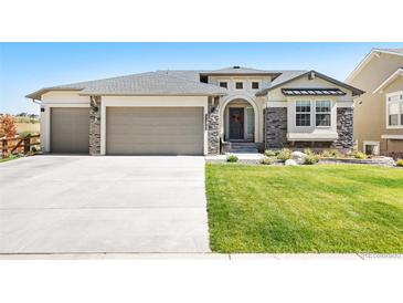 Inviting home featuring a manicured lawn, stone accents, arched entrance, and a spacious three-car garage at 15773 Timber Trek Way, Monument, CO 80132