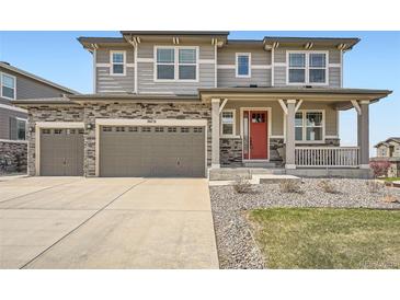Two-story home featuring stone accents, three-car garage, covered porch and red front door at 26731 E Hinsdale Pl, Aurora, CO 80016