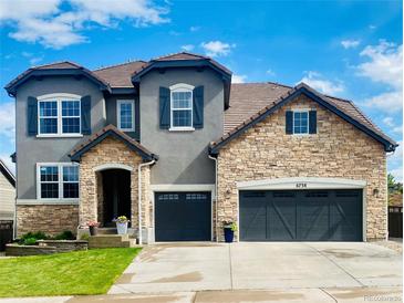Beautiful two-story home with stone and stucco exterior, three-car garage, and well-manicured lawn at 6738 Esmeralda Dr, Castle Rock, CO 80108