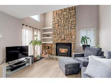 Inviting living room with a stone fireplace, modern furniture, bright windows, and neutral paint creating a warm atmosphere at 12430 E Pacific Cir # B, Aurora, CO 80014