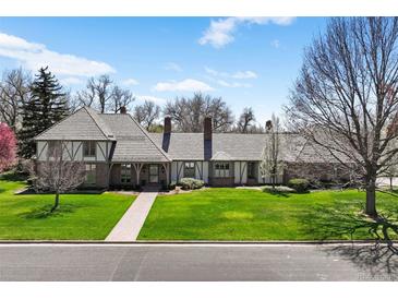 Charming two-story home featuring lush green lawn, beautiful landscape, and a brick pathway leading to the front door at 21 Huntwick Ln, Cherry Hills Village, CO 80113