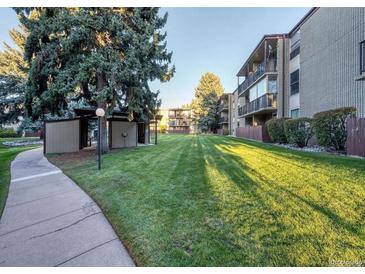 Building exterior shows large grassy area with mature trees and walkway at 2281 S Vaughn Way # 118A, Aurora, CO 80014