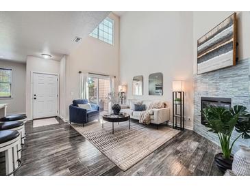 Bright living room featuring a high ceiling, modern fireplace, and stylish furnishings at 3611 S Perth Cir # 103, Aurora, CO 80013