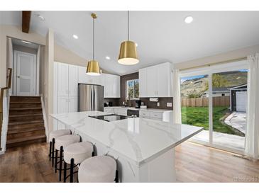 Bright, remodeled kitchen with island seating, stainless appliances, and sliding door access to backyard at 18866 W 59Th Pl, Golden, CO 80403