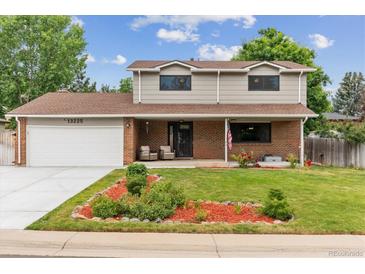 Charming two-story home featuring manicured front yard, brick facade, and covered porch with seating area at 13225 Peacock Dr, Lone Tree, CO 80124
